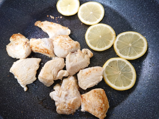 フライパンにオリーブオイルとにんにくを入れ、鶏肉の表面を焼く。両面に焼き色がついたら、輪切りのレモンを入れて、軽く焼く。