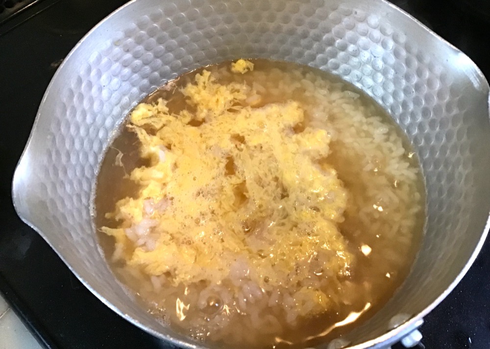 鍋に分量の水を調味料を入れ、一煮立ちさせた所に②のご飯を入れる。沸騰してきたら、そこに割りほぐした卵を入れる。