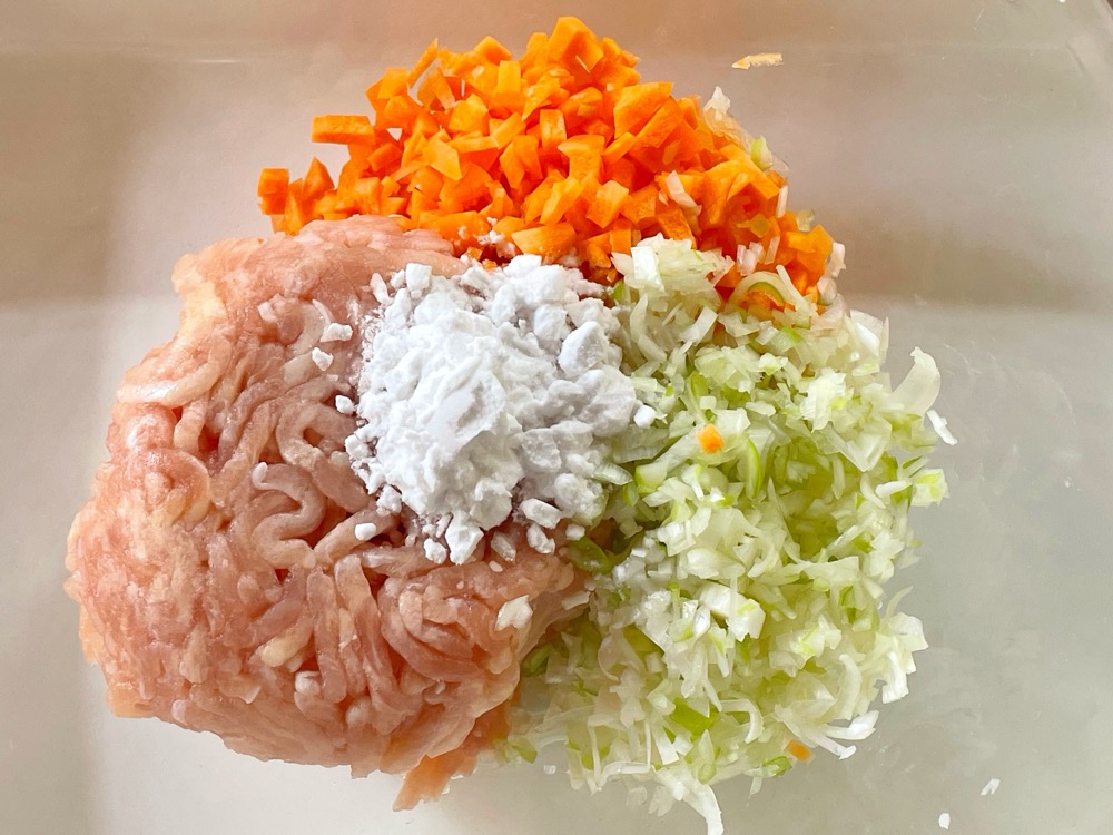 鶏ひき肉に、みじん切りのねぎとにんじん、片栗粉、塩と酒、生姜汁を入れてよくこねてから2つに分ける。