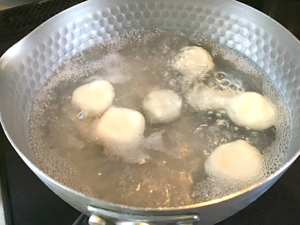 ②を直径2㎝くらいのボール型にし、真ん中を押し潰し、沸騰したお湯の中で茹でる。お湯の中で浮き上がってきたら、冷水の中に取り出す。