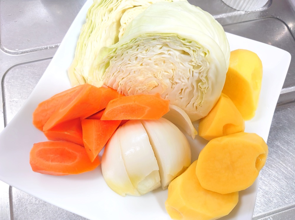 じゃがいもは1/2～1/4サイズに切り、玉ねぎは大きめのくし切りにする。にんじんは大きめの乱切りにする。キャベツは芯を残したまま半分に切る。