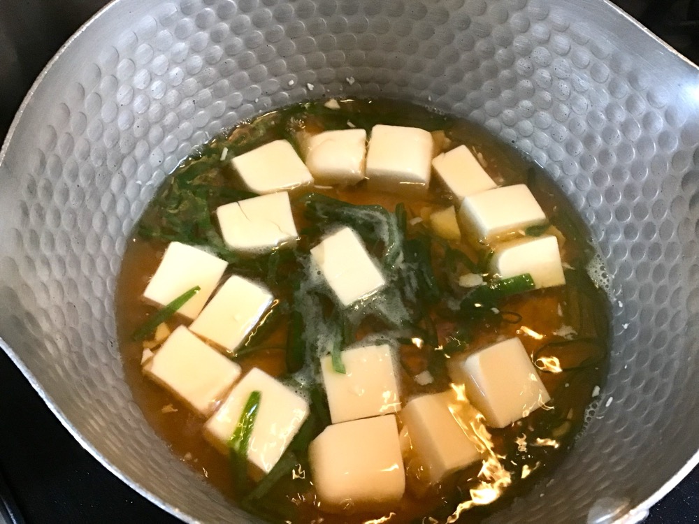 小鍋に分量の水と片栗粉以外の調味料を入れる。その中に小口切りにしたねぎとサイの目切りにした豆腐を入れる。