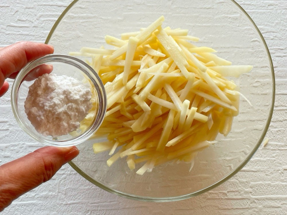 じゃがいもは皮をむいて細めの千切りにし、洗わないでボウルに入れる。ひとつまみの塩（分量外）を入れてよく混ぜ、片栗粉を入れてよく混ぜる。