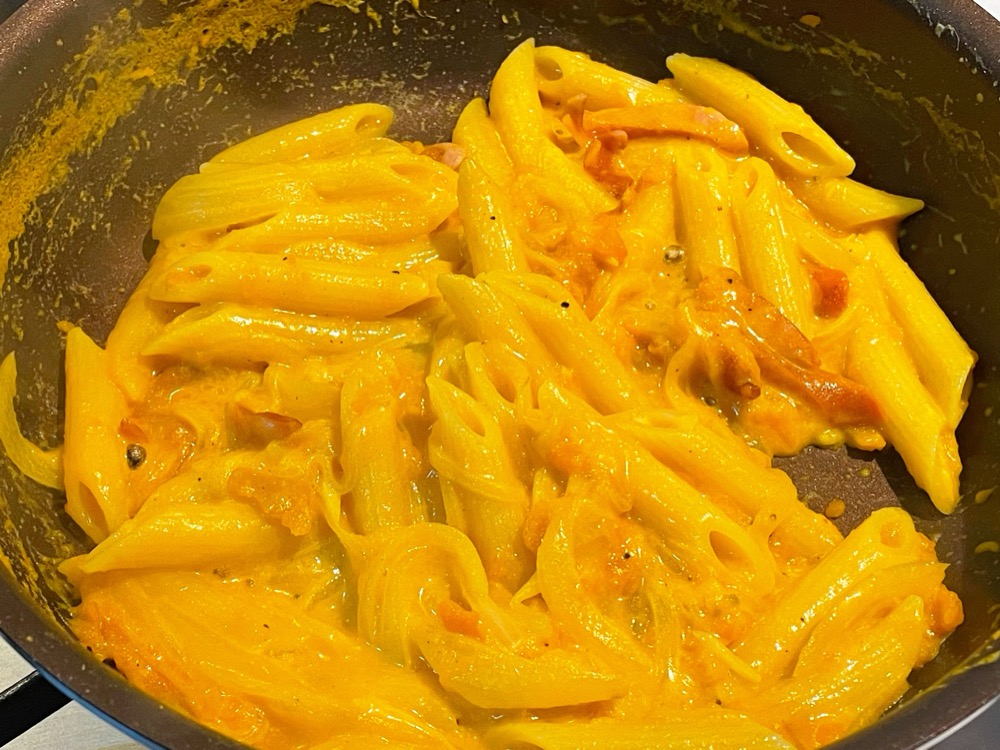 クリームソースにペンネを加えて、好みのとろみになるまで揺すりながら煮詰める。ひとつまみの塩と黒こしょうで味を引き締める。