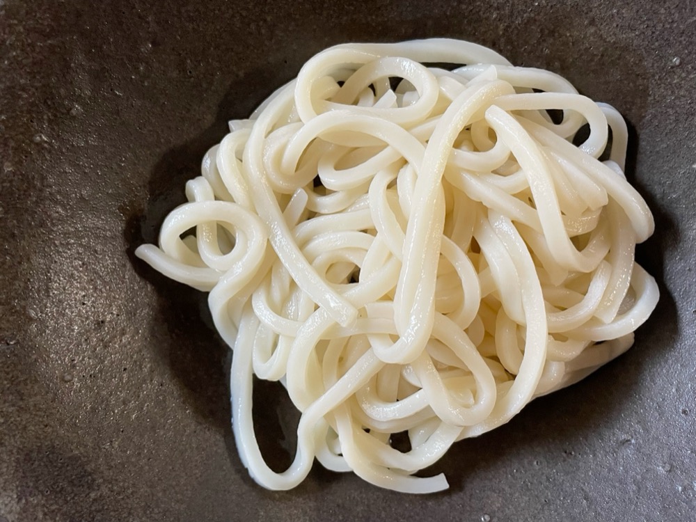 冷凍うどんは袋に書いてある時間加熱して、皿に盛り付ける。