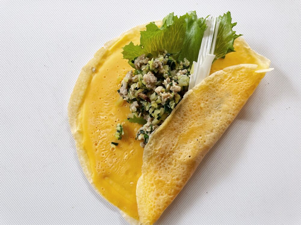 ギョウザ味の方は、クレープにレタスを敷き、炒めた鶏挽肉をたっぷり盛り付け、あれば白髪ねぎを加えてくるりと巻く。