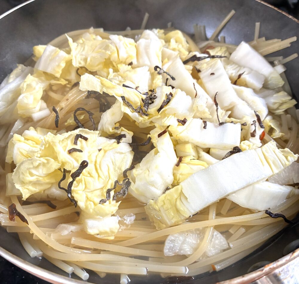 <span class="textImageBlock_processNumber">2</span>の水分が半分位になったら、ざく切りにした白菜と塩昆布を入れる。