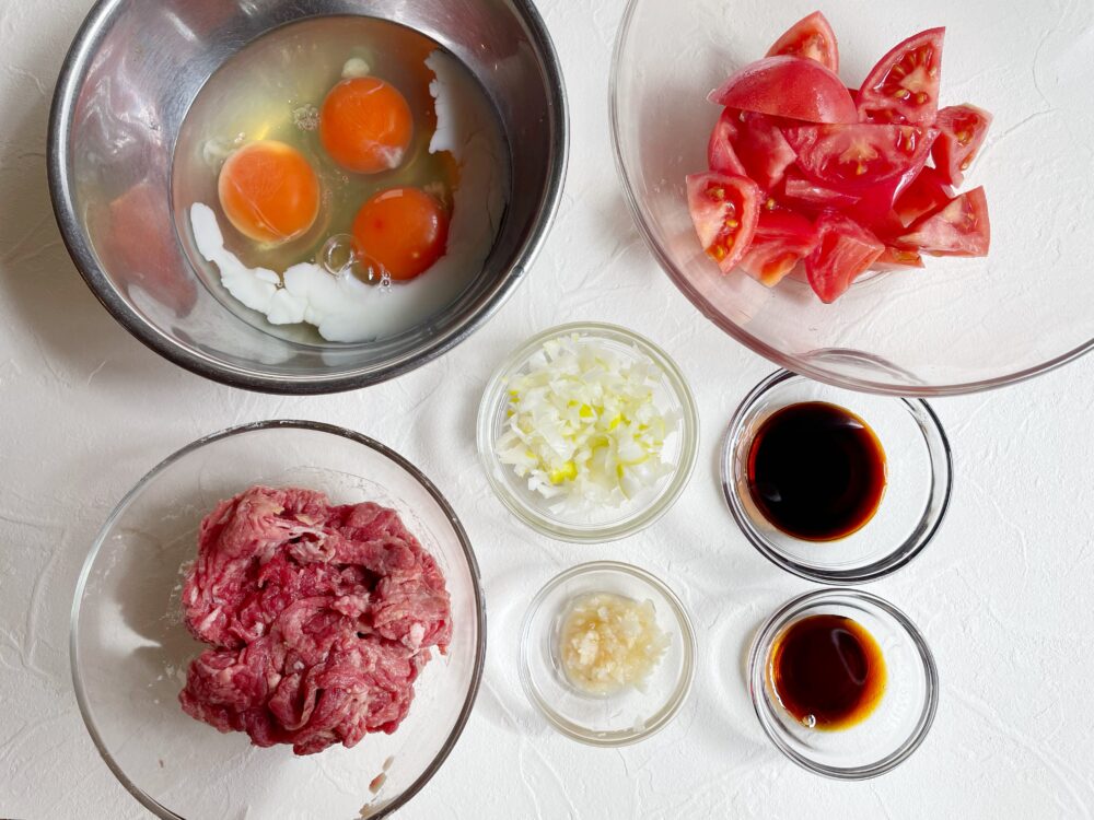 牛肉は食べやすい大きさに切って醤油・酒・片栗粉をまぶす。ねぎはみじん切り。にんにくと生姜もみじん切りにする。卵に豆乳（もしくは酒）を加える。トマトは食べやすい大きさに切る。