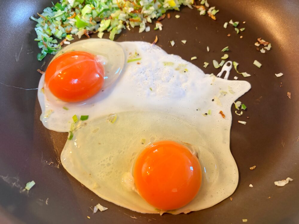 炒めていた具を片側に寄せて火を強め、卵を割り落とす。