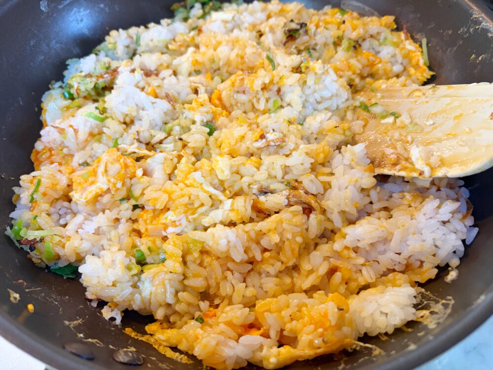 卵全体に火が通ったら、フライパンの片側にチャーハンを寄せて、空いたところに醤油を落とし、醤油を焦げさせてから全体を混ぜ合わせる。