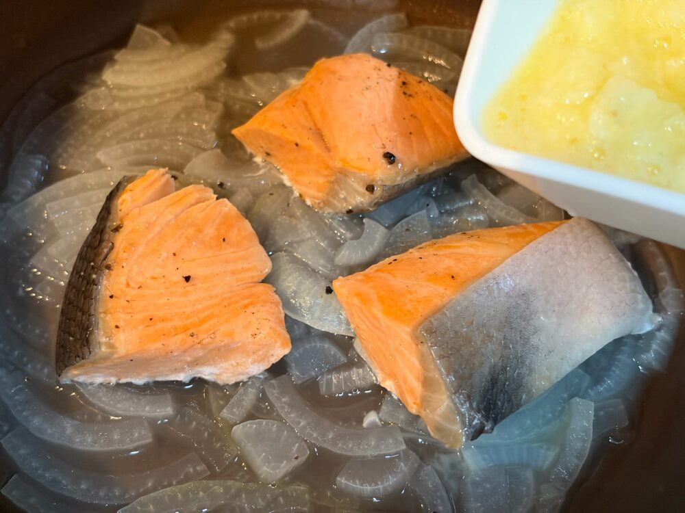じゃがいもをすりおろしてフライパンに加え、牛乳とコンソメを加えて混ぜ、蓋をして3～4分弱火にかける。
