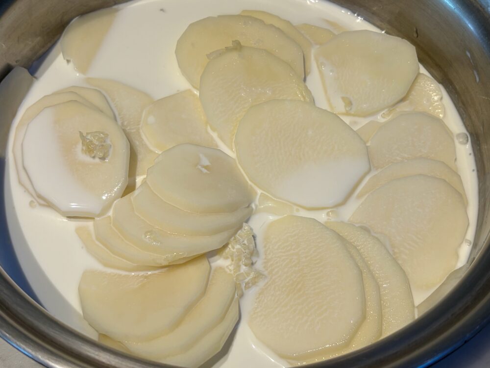 薄切りのじゃがいもを鍋に入れ、豆乳、にんにく、塩を加えて蓋をして、火にかける。