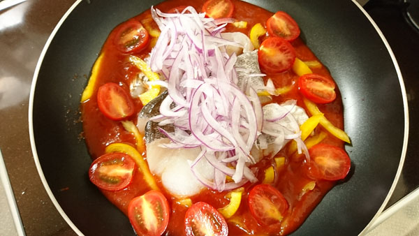 フライパンにトマトソースを入れて、白身魚を並べ、上に紫玉ねぎをのせる。周りにミニトマト、パプリカを散らす。蓋をして中火で6分蒸し煮にする。
