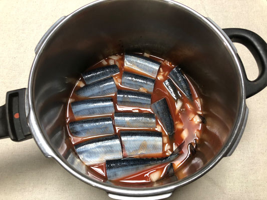 圧力鍋にトマト缶、水、塩、2を入れたら、さんまを並べる。