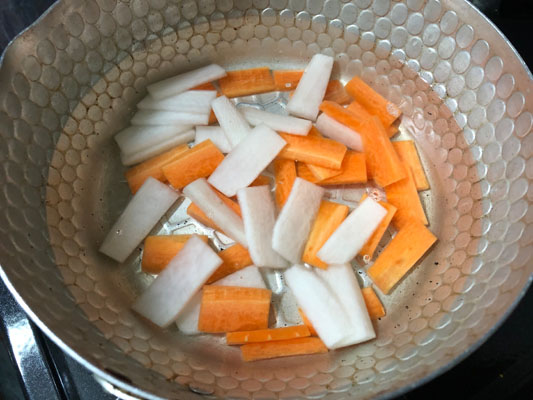 にんじんと大根を鍋に入れてから火にかけ、柔らかくなったら、白菜を入れ、醤油・みりんを加える。