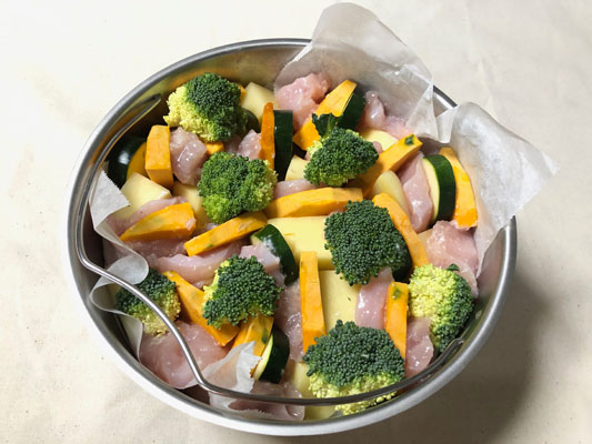 蒸し器にクッキングシートを敷き、野菜と鶏胸肉を詰める。